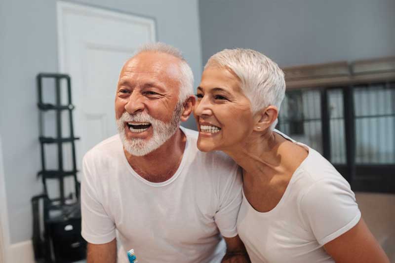 Older couple smiling after dental implants in Los Nogales dental clinic